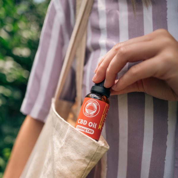 A hand pulling a 1500mg Full Spectrum CBD Oil Tincture from a tote bag