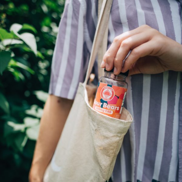 A person placing Sunset Lake's CBD Gummies into a tote bag