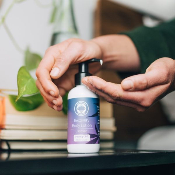 Two hands dispensing CBD lotion from a pump bottle