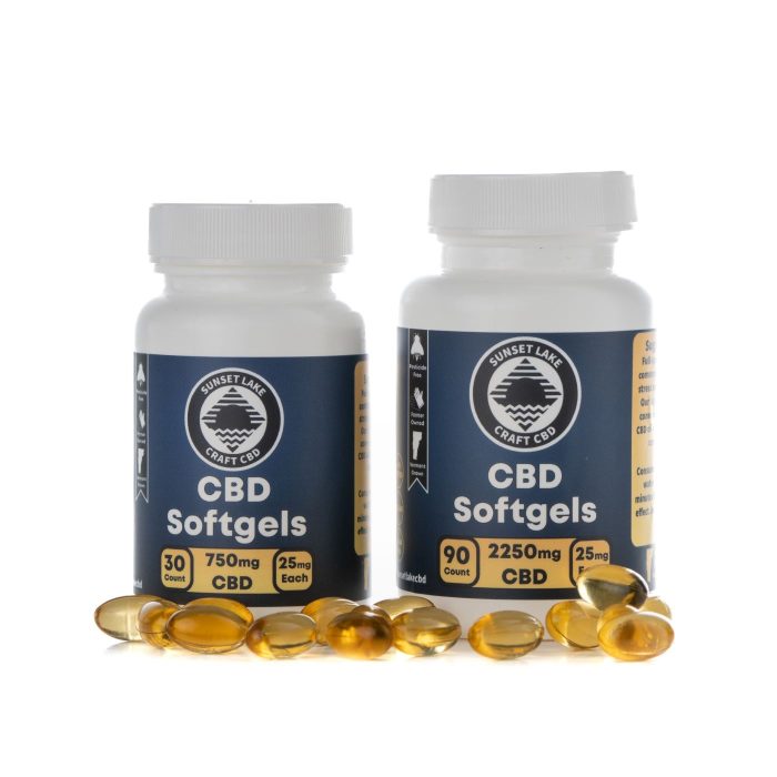Two bottles of CBD softgels surrounded by loose softgel caps