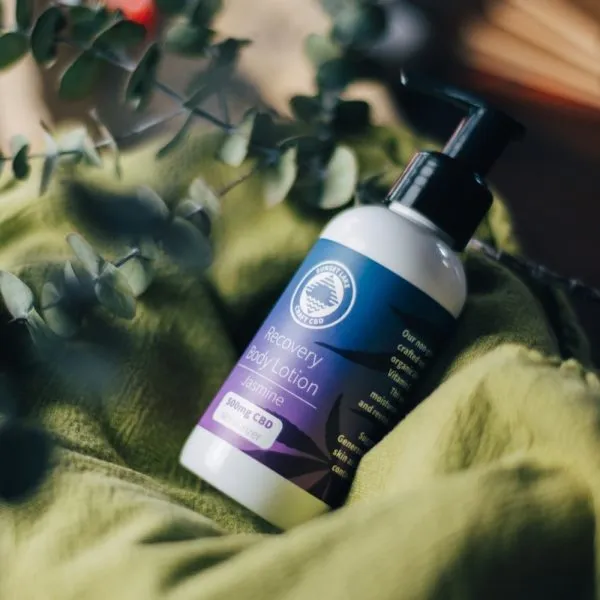 A bottle of CBD lotion laying on a green blanket