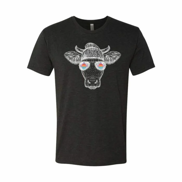A graphic T-shirt featuring a cow wearing sunglasses embossed with the Sunset Lake retro logo